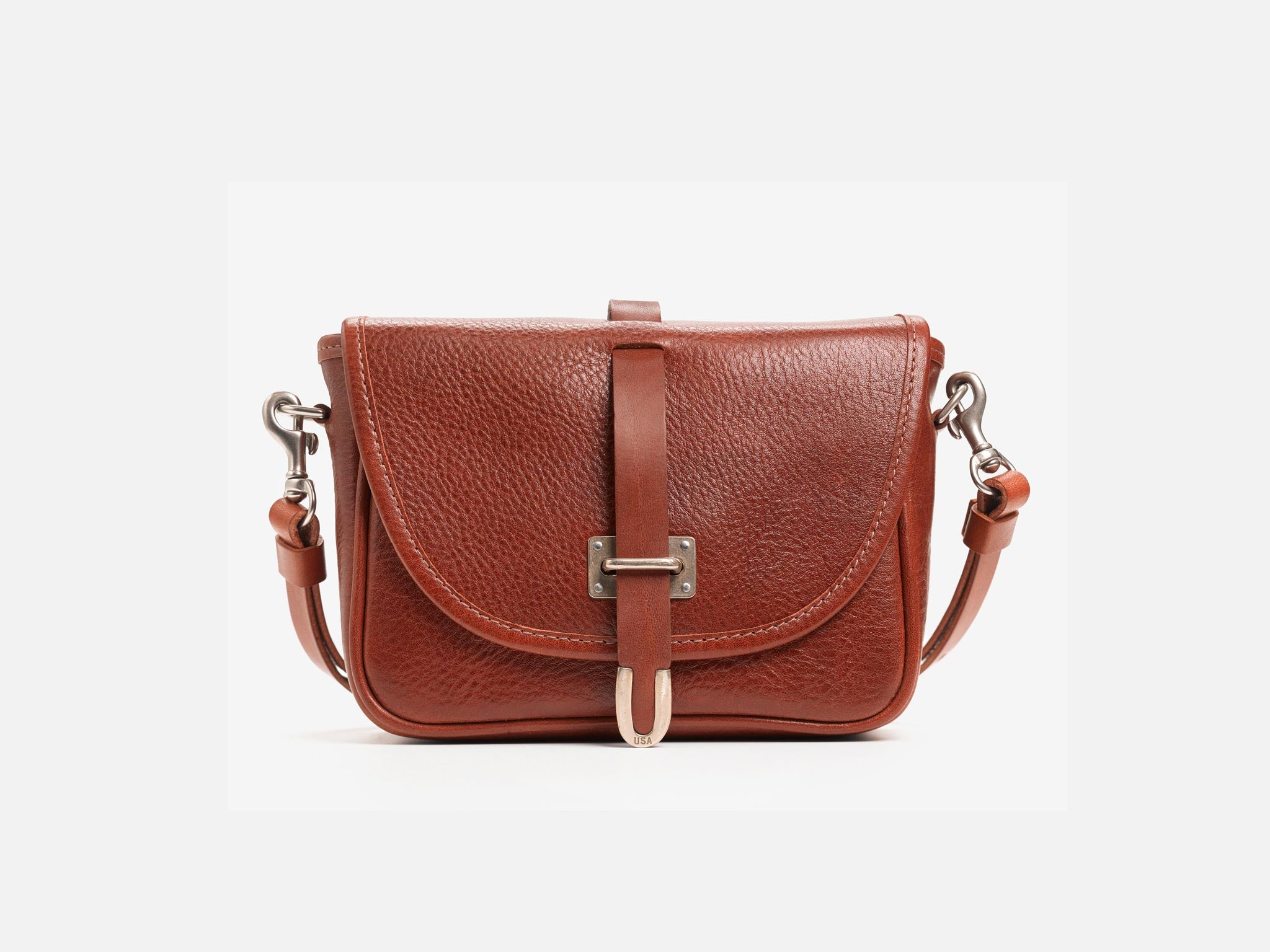 A small brown leather crossbody bag with a front flap, silver hardware, and an adjustable shoulder strap, displayed against a plain white background.