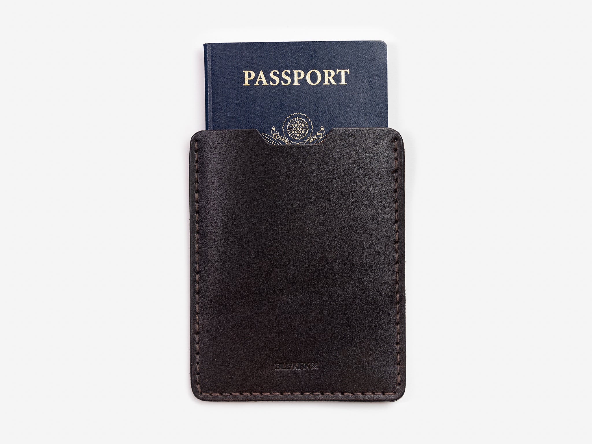 A dark brown leather passport holder with a navy blue passport partially visible inside, both placed against a plain white background.