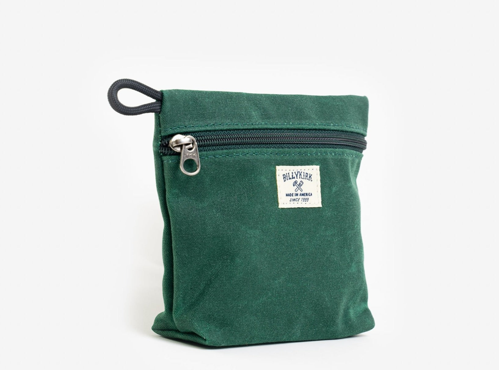 A green waxed canvas pouch with zipper closure on a neutral background. It features a cream woven tag that reads "Billykirk made in america since 1999".