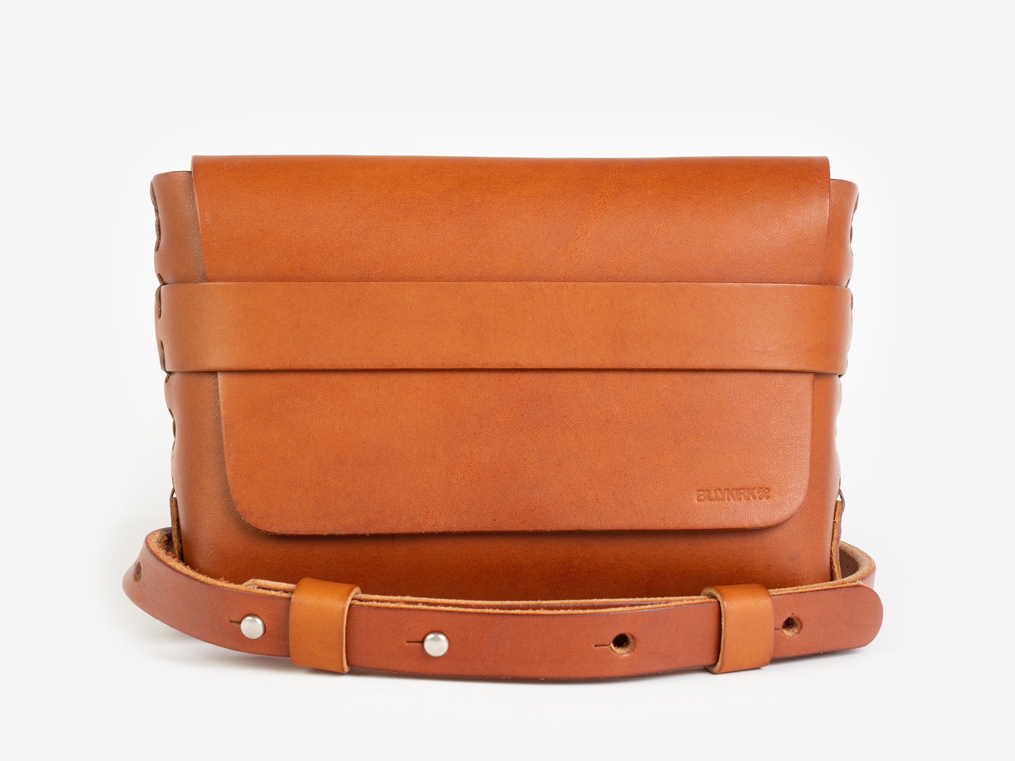 A tan leather belt crossbody bag with a smooth finish, featuring a flap closure, subtle embossed branding, and an adjustable strap with silver-tone collar buttons, displayed against a white background.