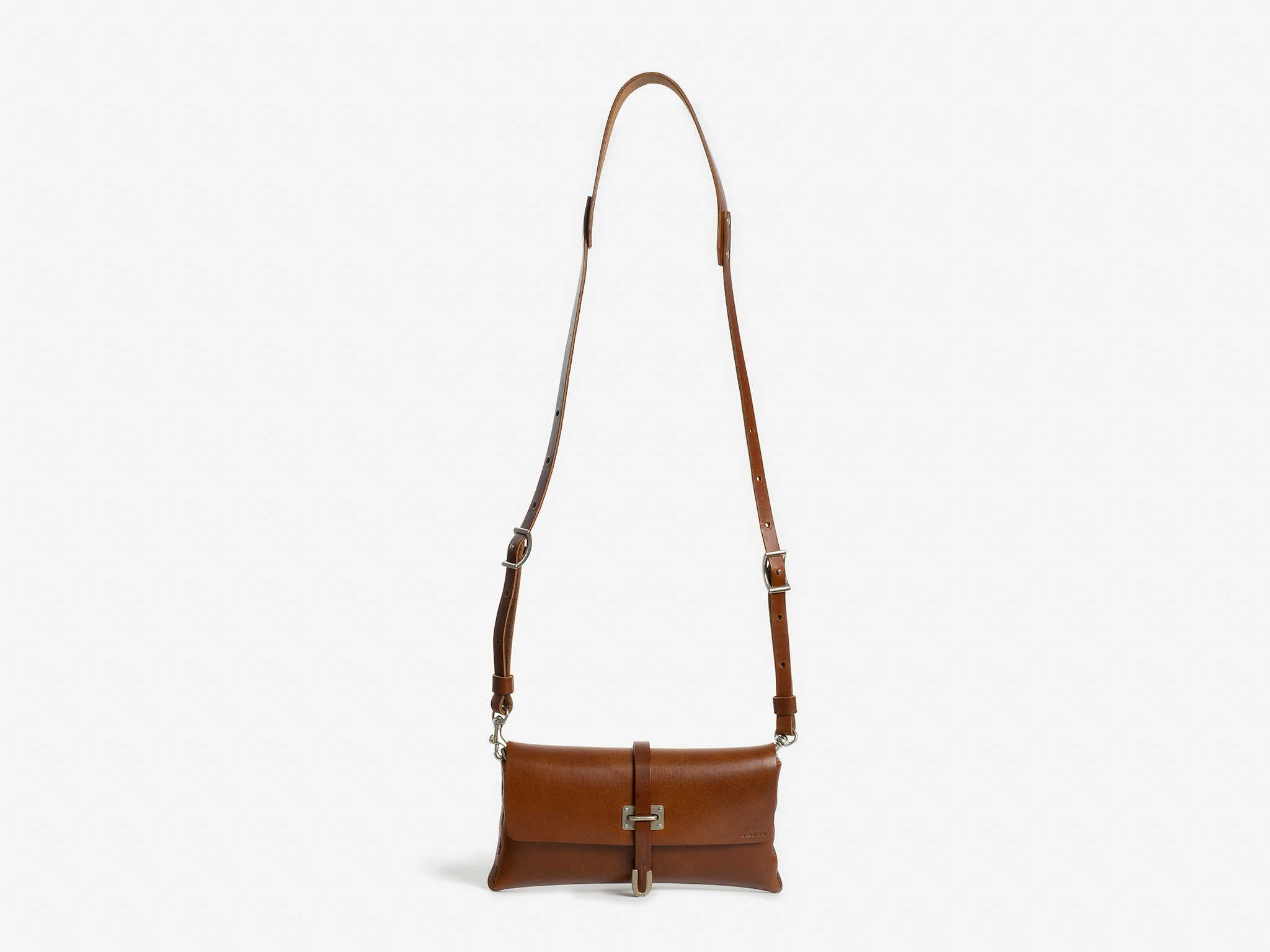 A brown leather crossbody bag with an adjustable strap and a rectangular shape, featuring a metal clasp on the front. The background is plain white.