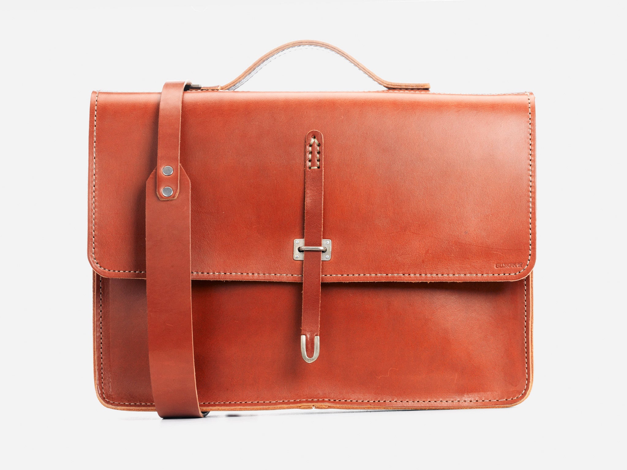 A brown leather briefcase with a top handle and a shoulder strap, featuring a front flap secured by a metal clasp and a vertical leather strap, displayed against a plain white background.